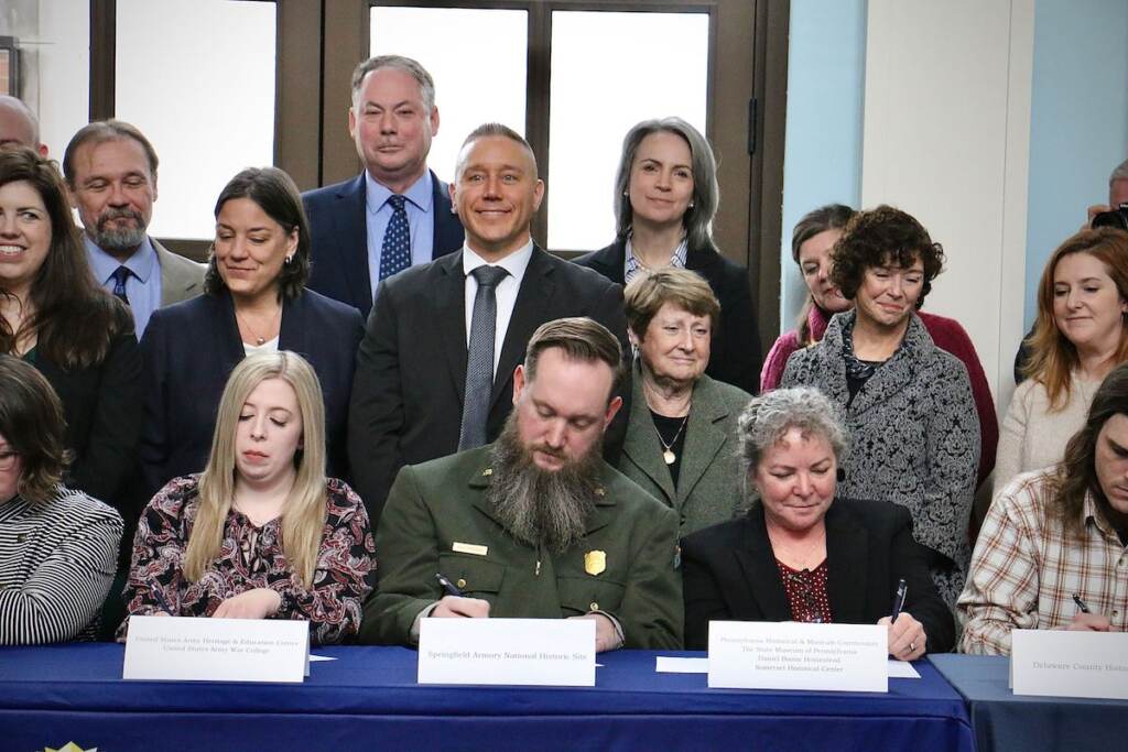 Representatives of 16 museums and historical societies sign documents accepting the return of 50 artifacts, mostly guns, stolen 50 years ago and returned during a ceremony at the Museum of the American Revolution