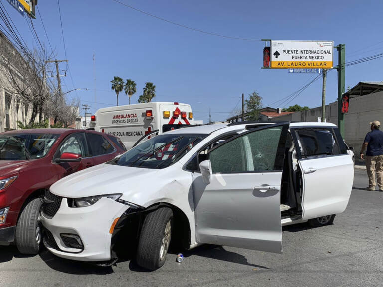A member of the Mexican security forces stands next to a white minivan with North Carolina plates and several bullet holes at the scene of the crime in Matamoros on Friday. (STR/AP)