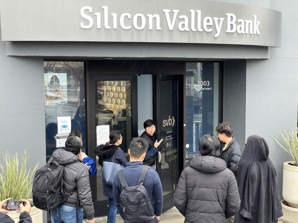 A worker (center) tells people that the Silicon Valley Bank (SVB) headquarters is closed