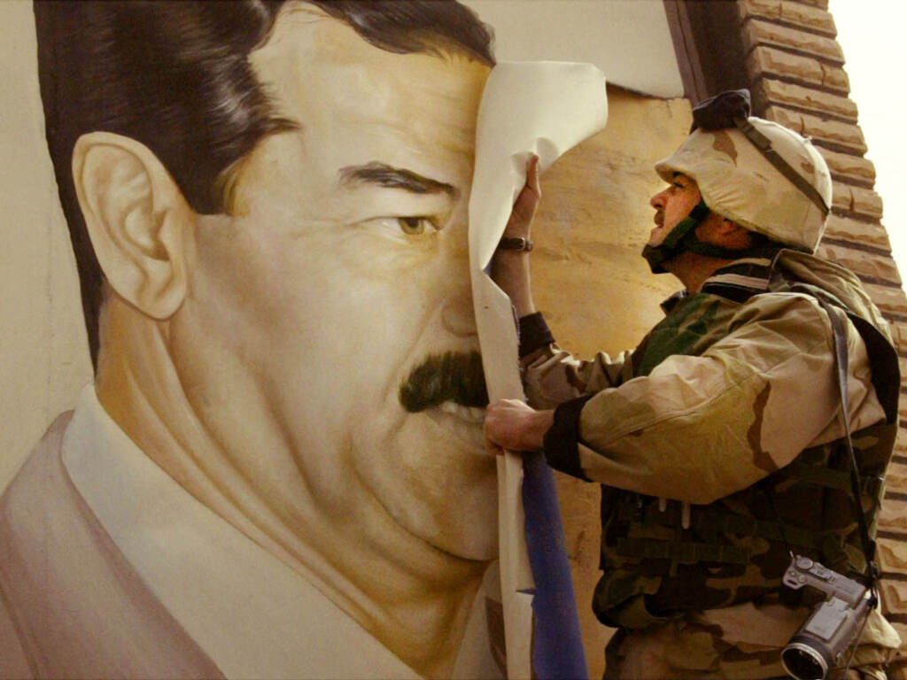 U.S. Marine Maj. Bull Gurfein pulls down a poster of Iraqi President Saddam Hussein on March 21, 2003, a day after the start of the U.S. invasion, in Safwan, Iraq. A soldier takes down a poster on a wall of Sadam Hussein.