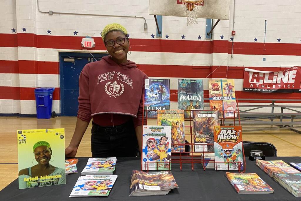 Ariell Johnson smiles at a table inside of a gym.