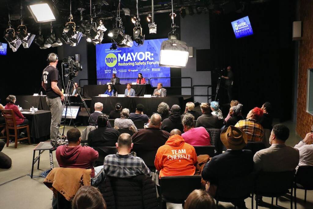 mayoral-forum-restoring-safety-3 An audience watches mayoral candidates on a stage at a forum.