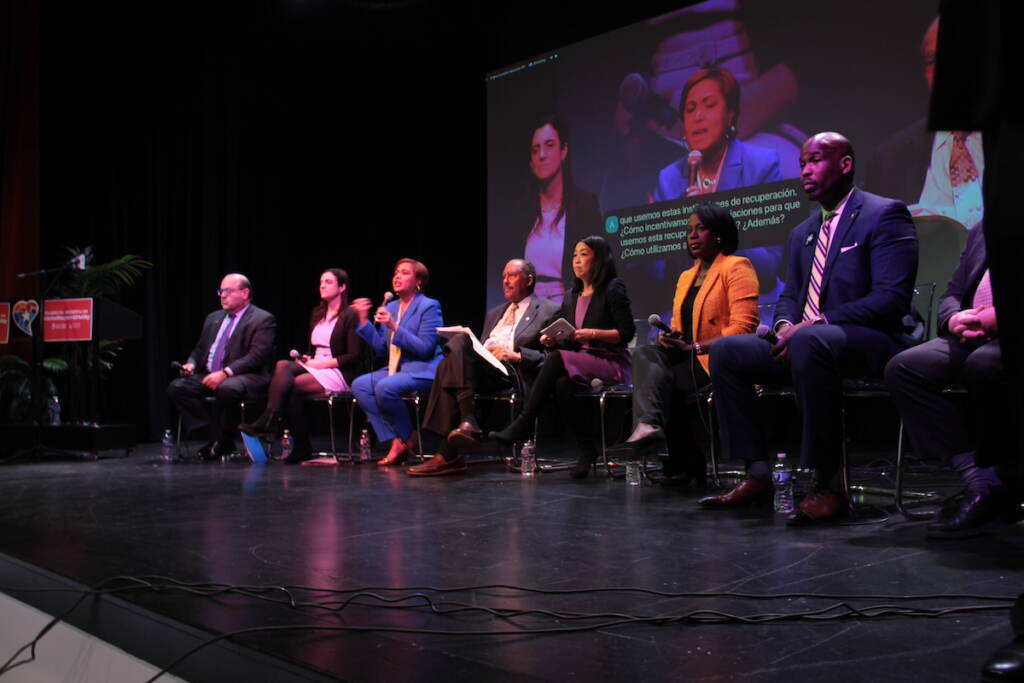 mayoral-race-arts-forum-2 Mayoral candidates are seated in a row in chairs on a stage.