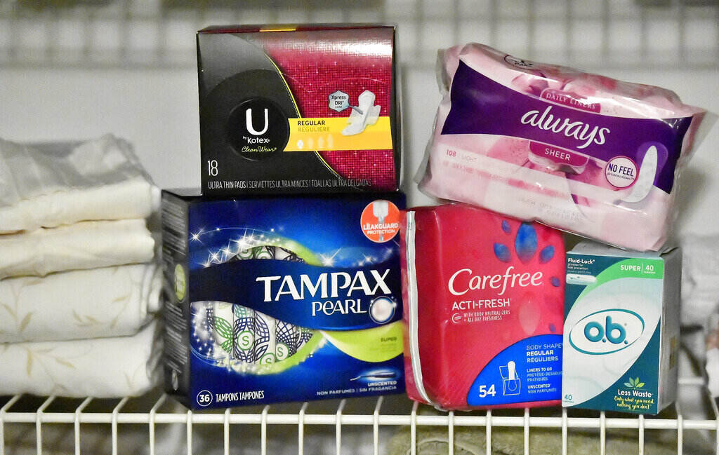 Menstrual Products in Schools Several boxes of pads and tampons are arranged on a shelf.