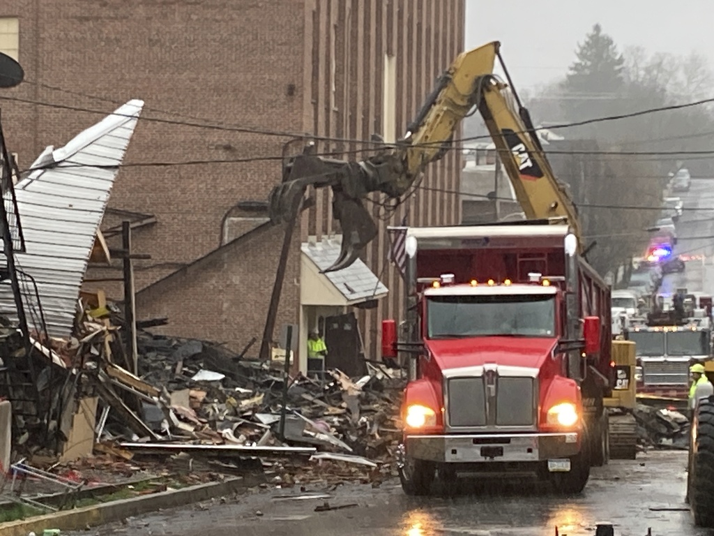 A fire truck outside of rubble on a street.