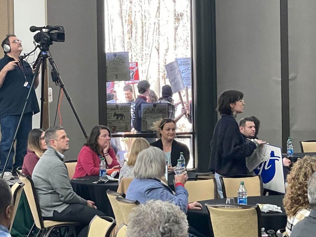 rutgers-protest-2 Protesters are visible through the windows of a meeting room.