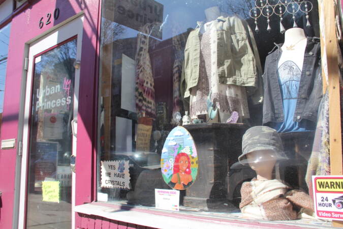 An egg design is seen in a store window displaying clothing on mannequins.
