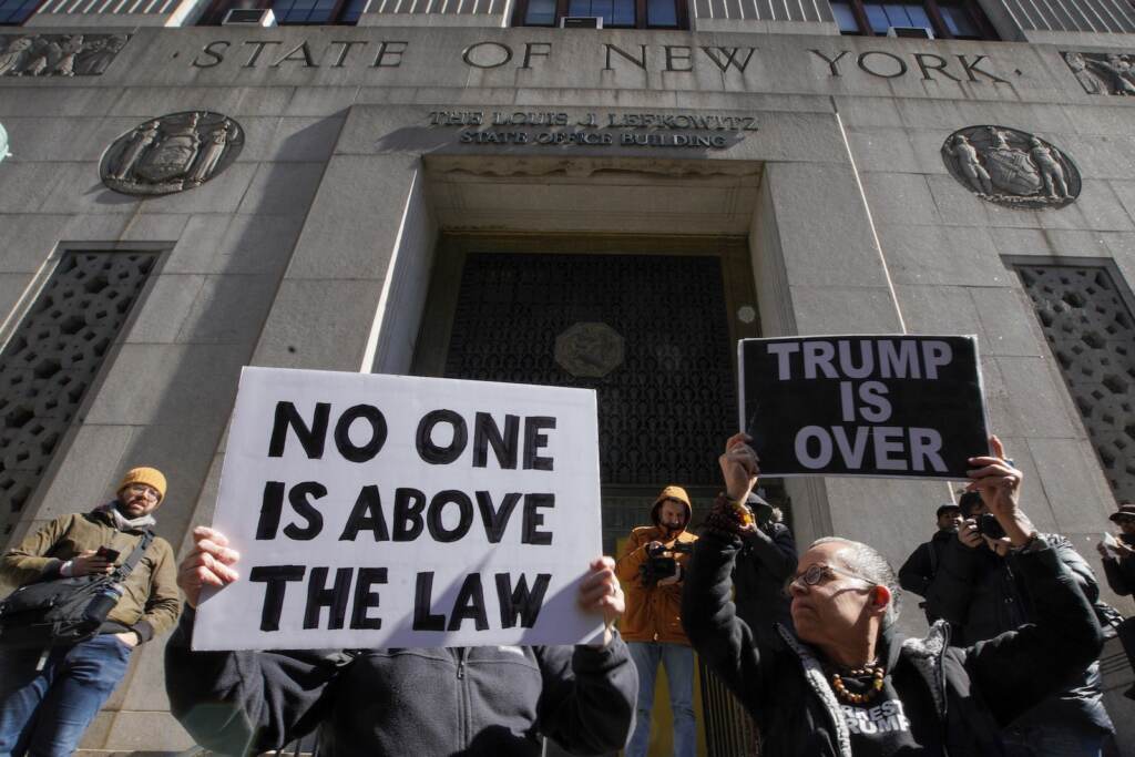 Trump Legal Troubles People hold up posters as part of a protest in front of the courthouse ahead of former President Donald Trump's anticipated indictment