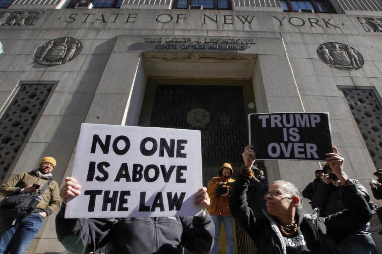 People hold up signs, including one that says 