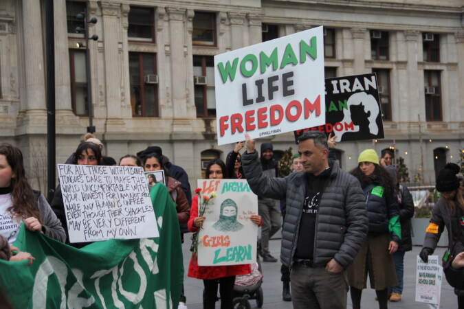 People hold signs, including one that says 