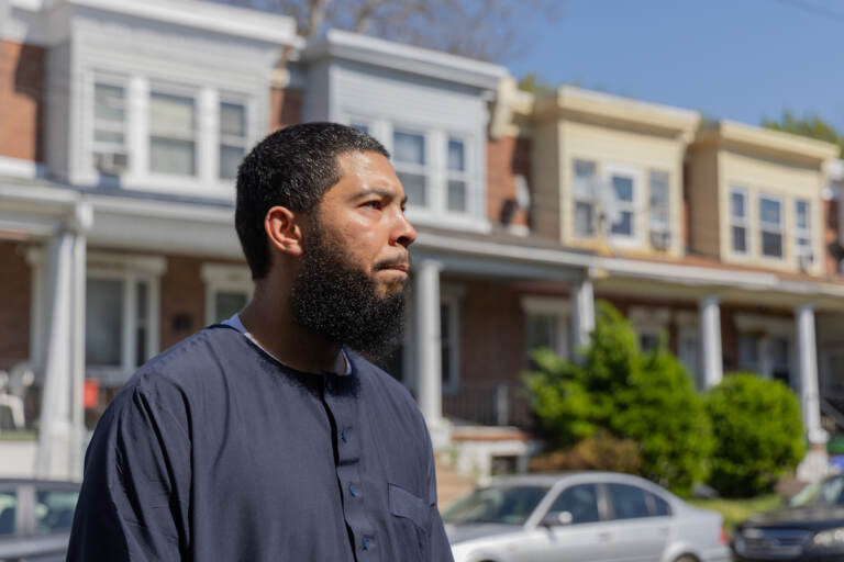 Anthony Freeman looks into the distance. Behind him is a row of houses.