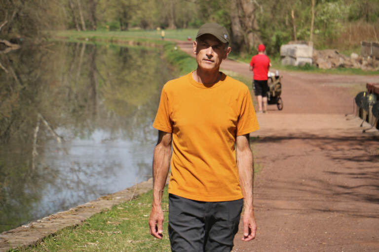 Neil King walking on a path along a river.
