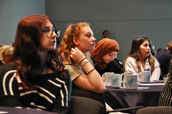 High school students look forward, listening to a speaker.