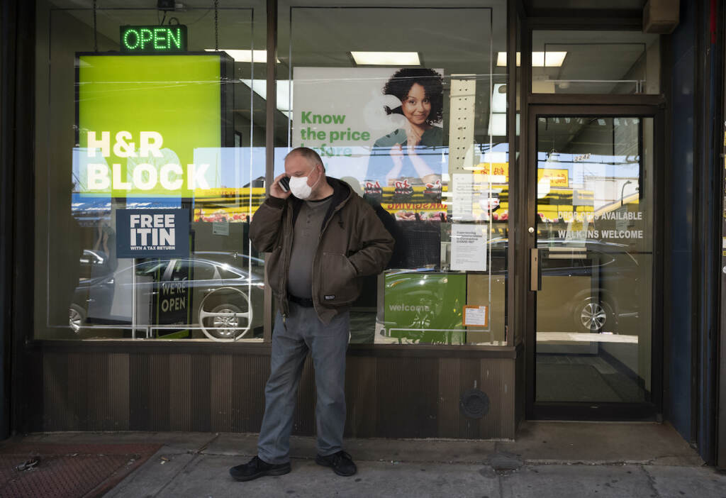 Financial Wellness Tax Season A man waits outside a H&R Block tax preparation office