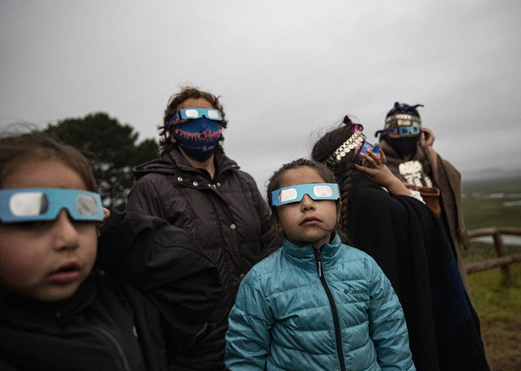 A Mapuche Indigenous family uses special glasses to try and observe a total solar eclipse in Carahue, La Araucania, Chile, Monday, Dec. 14, 2020. The total eclipse was barely visible from Carahue because of an overcast sky. A Mapuche Indigenous family uses special glasses to try and observe a total solar eclipse in Carahue, La Araucania, Chile, Monday, Dec. 14, 2020. The total eclipse was barely visible from Carahue because of an overcast sky. (AP Photo/Esteban Felix)