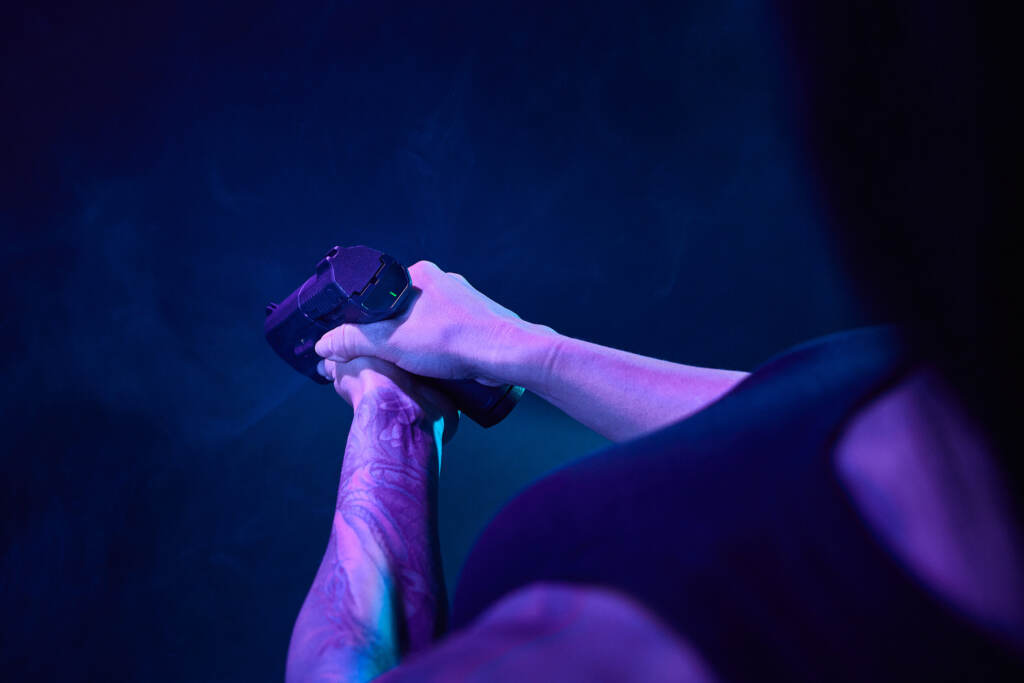 A person holds a gun in front of htem.