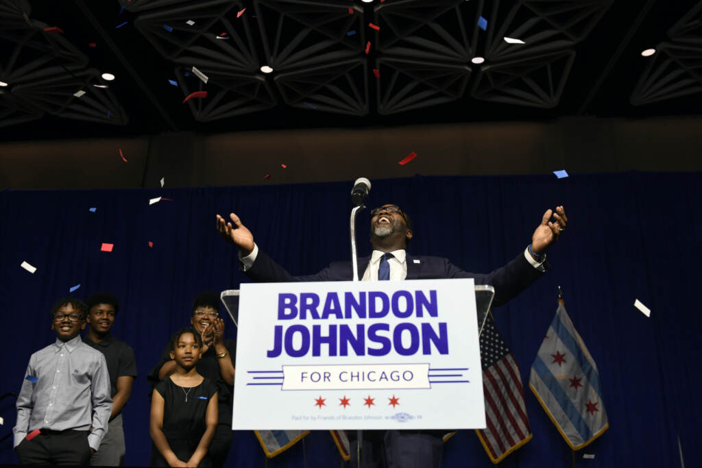Brandon Johnson on stage with confetti falling after winning.
