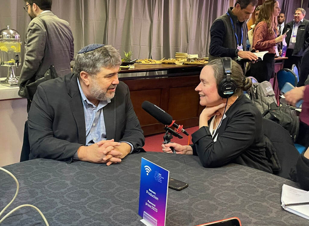 Susan Phillips speaks with OurCrowd CEO Jon Medved at a table in a conference room.