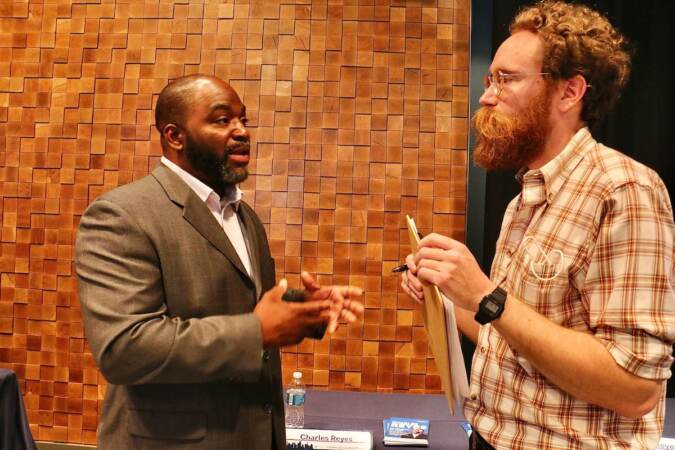 Philadelphia City Council candidate Charles Reyes (left) talks with voters at a candidate convention hosted by WHYY. (Emma Lee/WHYY)