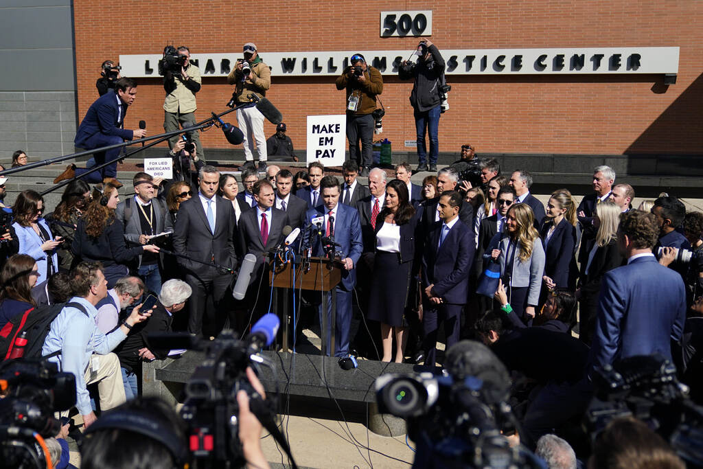 Fox Dominion Lawsuit People stand in a group surrounded by cameras and news reporters.