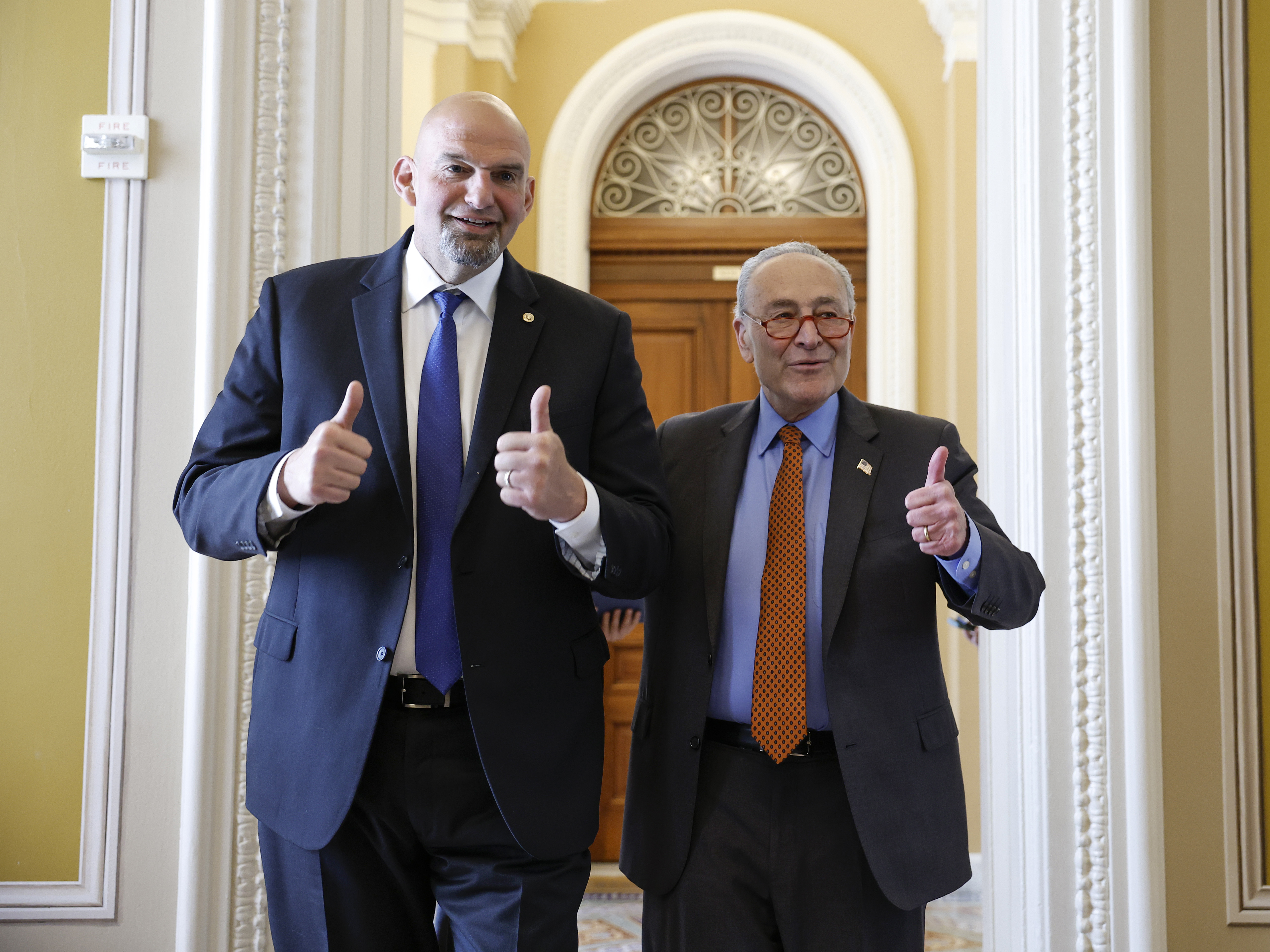 Sen. John Fetterman and Senate Majority Leader Chuck Schumer give a thumbs up to reporters as they walk to the weekly Senate policy luncheons together at the U.S. Capitol Building on April 18