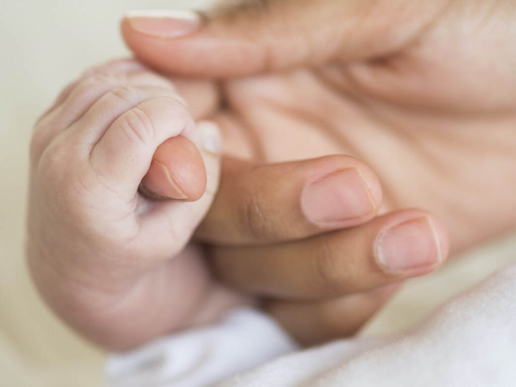 Hispanic mother holding infant’s hand Hispanic mother holding infant's hand