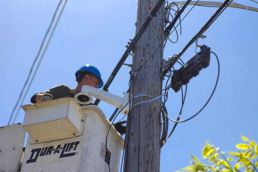 parks-camera-installation-t-macdonald-2023-04-12 A worker is setting up a security camera to a telephone poll.