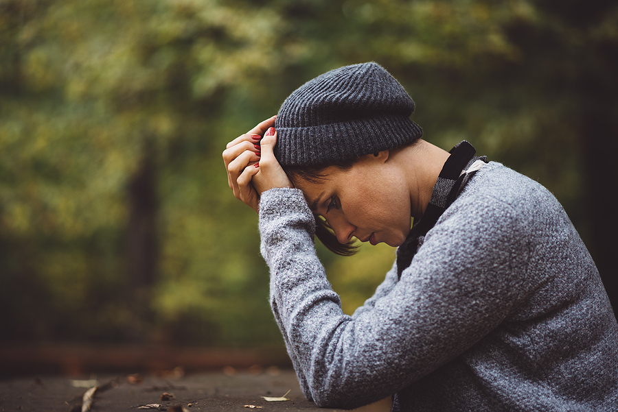 quarter-life-crisis-5 A person sits with their head in their hands in a forest.