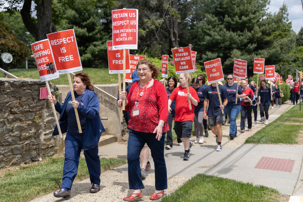05 19 2023 k paynter pasnap march crozer-chester nurse picket upland pa Protesters march on a sidewalk.