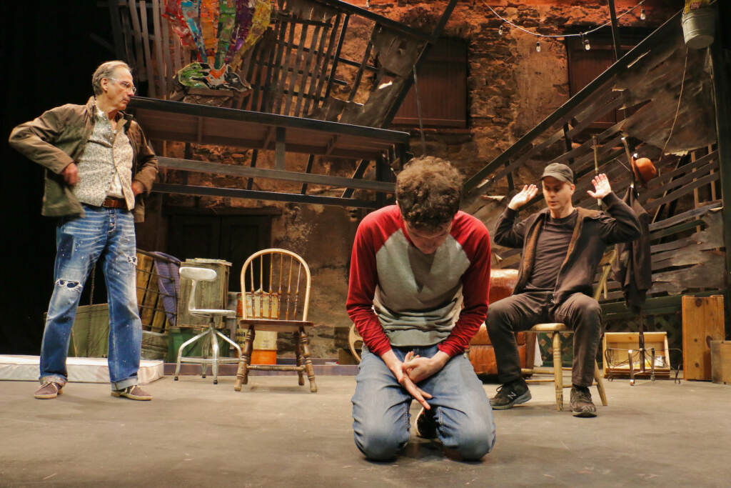 2023 05 19-e lee-david shiner michael stahler daniel passer-media pa hedgerow theatre-the puzzle autism Michael Stahler kneels onstage. Actors David Shriner and Daniel Passer look on behind him.
