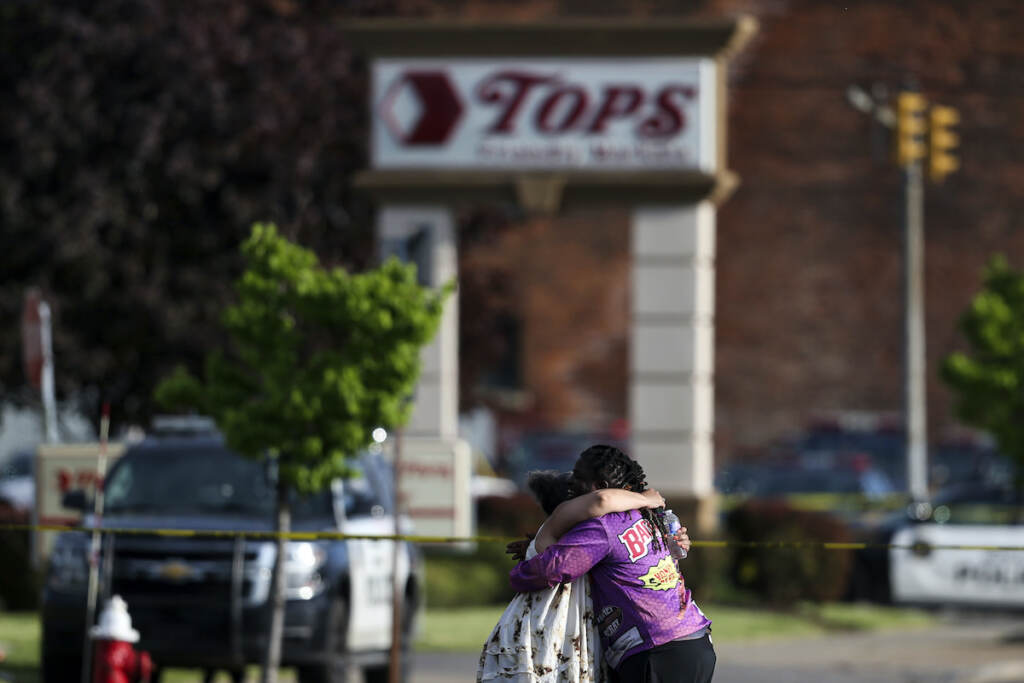 People hug outside the scene after a shooting at Tops supermarket, May 14, 2022, in Buffalo, N.Y. The city of Buffalo will pause Sunday, May 14, 2023 to mark the passing of one year since a gunman killed 10 people and injured three others in a racist attack that targeted Black people at a city supermarket