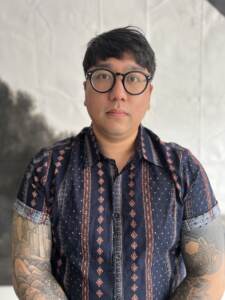 Acupuncturist Tyler Phan looks forward, wearing glasses, and a patterned short sleeved shirt. Credit: Nikie Belliveau