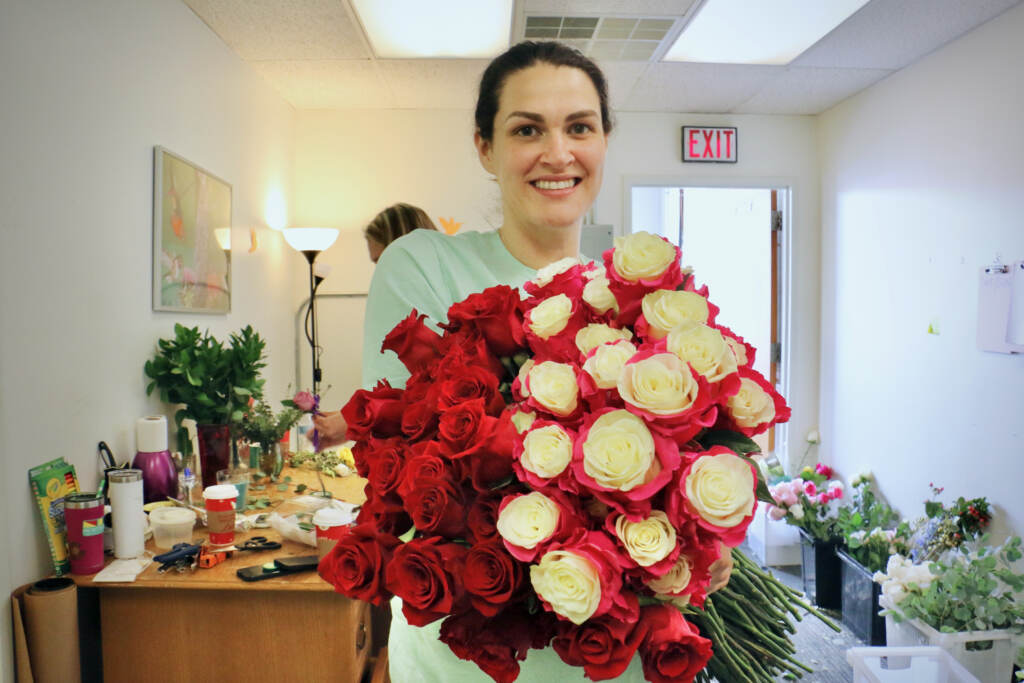Holly Alvarez of Holly Rose Wholesale florist in Mount Laurel, N.J., carries a bundle of roses that will be used to make Mothers Day bouquets for women whos children have died. Working with the Compassionate Friends of Camden County, Alvarez will deliver about 50 bouquets on Mothers Day. (Emma Lee/WHYY)