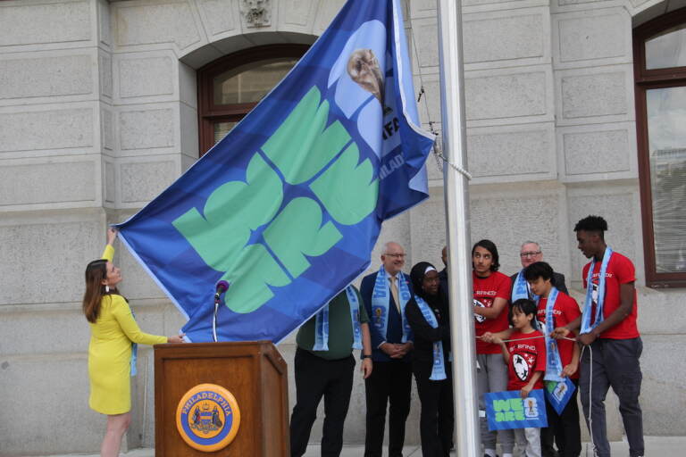 A group of people raise a FIFA World CUP flag.