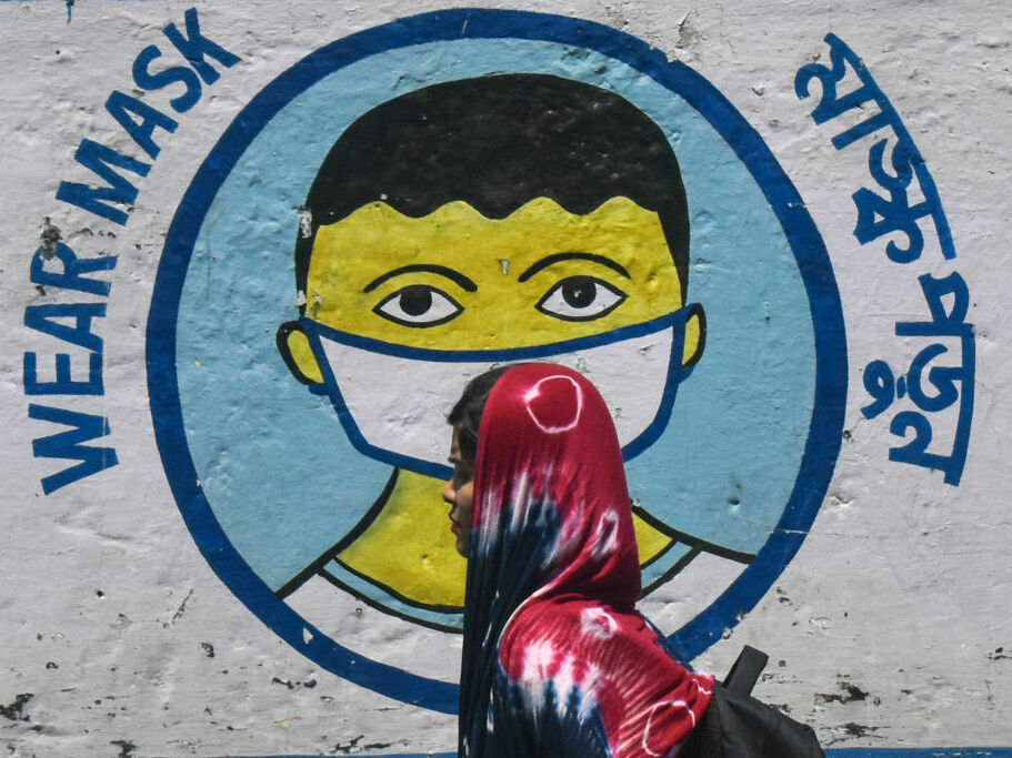A poster in Kolkata, India, from peak pandemic days sends a message to mask up. Now that the official COVID-19 global emergency is no longer in effect, some folks are thrilled to stop masking — but others wonder if it’s a good idea to keep up certain precautions. A poster in Kolkata, India, from peak pandemic days sends a message to mask up. Now that the official COVID-19 global emergency is no longer in effect, some folks are thrilled to stop masking — but others wonder if it's a good idea to keep up certain precautions. (NurPhoto via Getty Images)