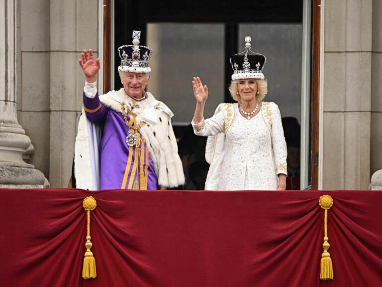 Britain's King Charles III wearing the Imperial state Crown, and Britain's Queen Camilla wearing a modified version of Queen Mary's Crown wave from the Buckingham Palace balcony after viewing the Royal Air Force fly-past in central London on Saturday. Oli Scarff/AFP via Getty Images