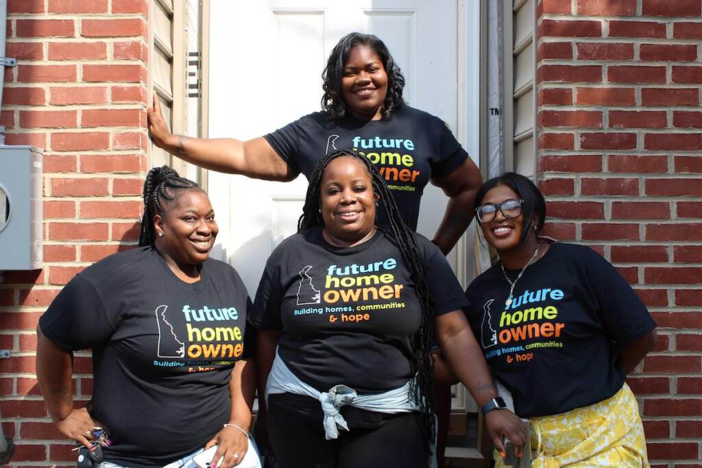 habitat-ncc-delaware People pose, smiling for a photo outside of a house.