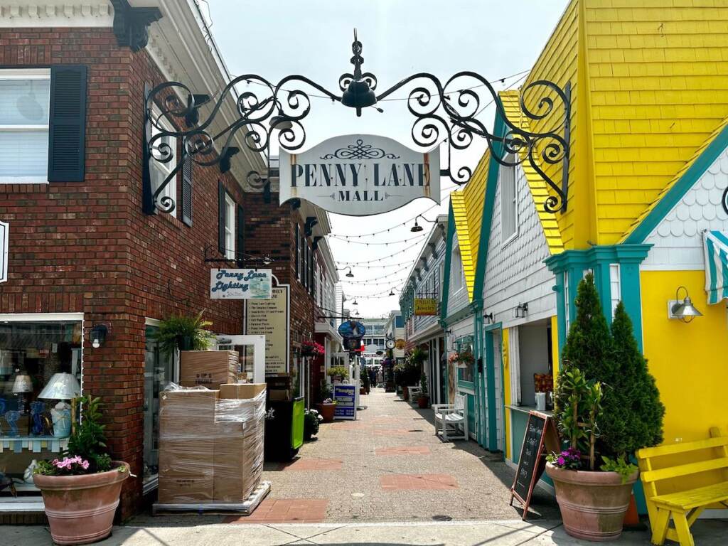 A row of stores on a brick lane. A sign reads Penny Lane.