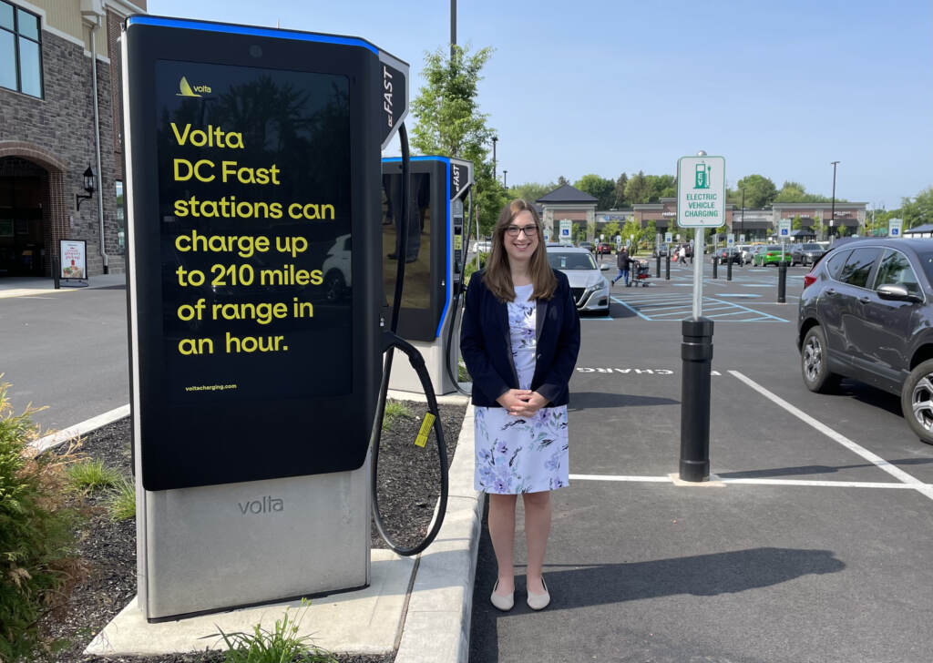 sarah M at charger Sarah McBride standing next to an electric vehicle charging station.