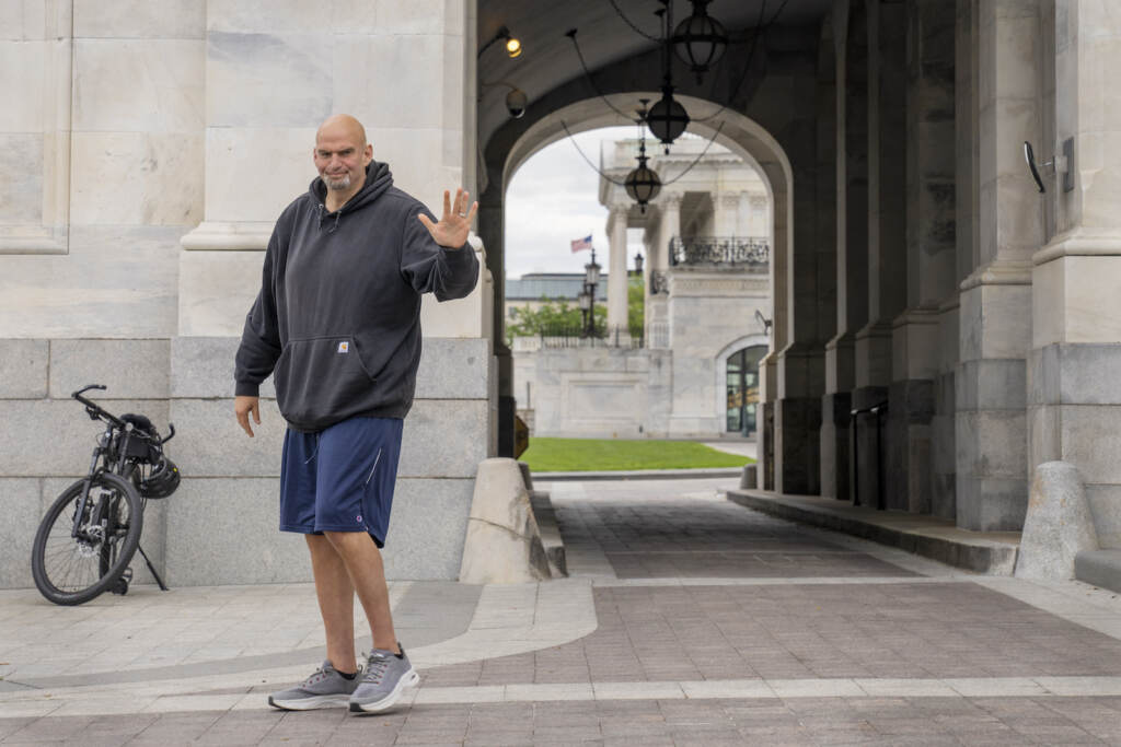 John Fetterman U.S. Sen. John Fetterman waves to the media while wearing gym shorts and a sweatshort