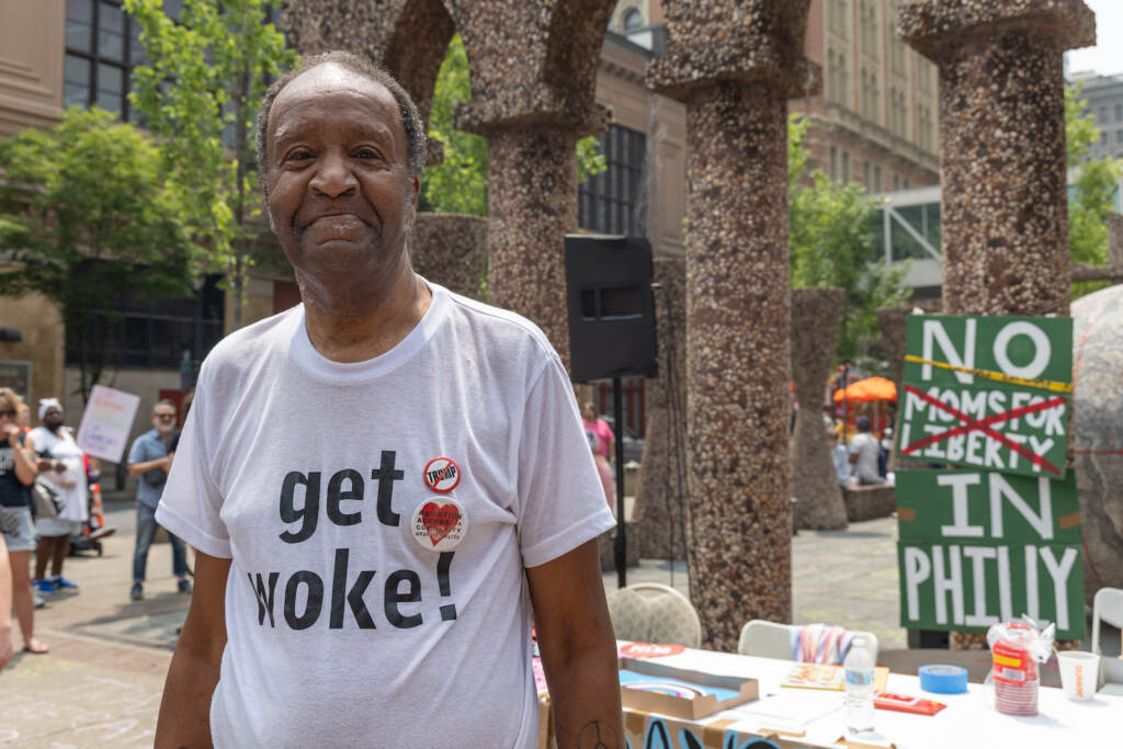 Eugene Carrington poses for a photo while wearing a shirt that says, ''Get woke''