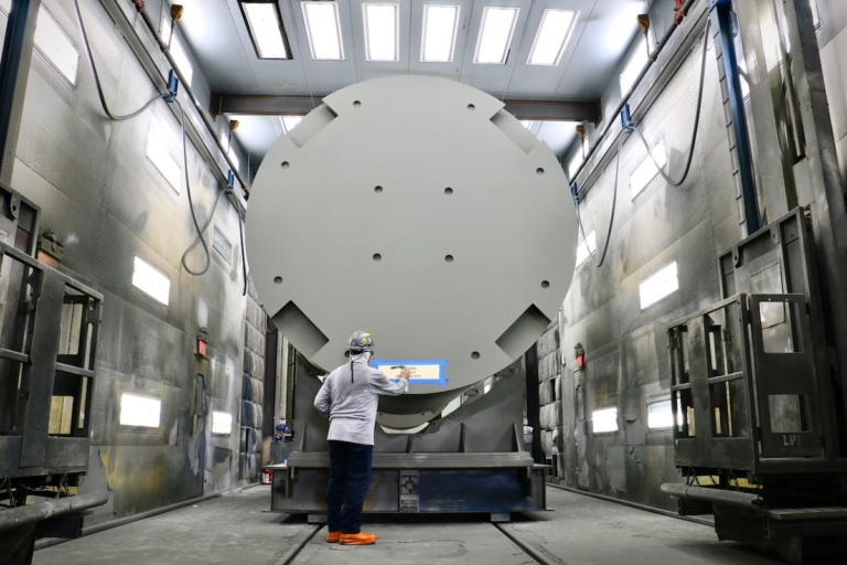 A worker stencils the destination on to fuel storage module at Holtec International in Camden. This one is headed for D.C. Cook Nuclear Plant in Michigan. (Emma Lee/WHYY)