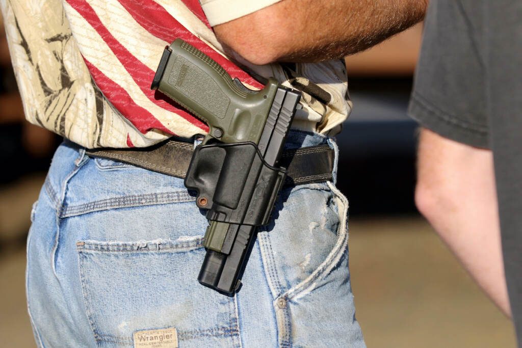 Oregon County Gun Vote In this Oct. 9, 2015 file photo, Michael Johnson wears a firearm as he waits outside of Roseburg Municipal Airport in Roseburg, Ore.