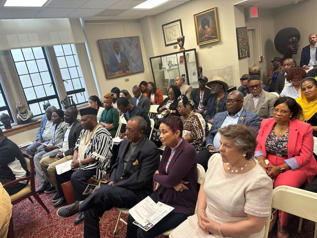 A crowd of people looks to the front of the room.