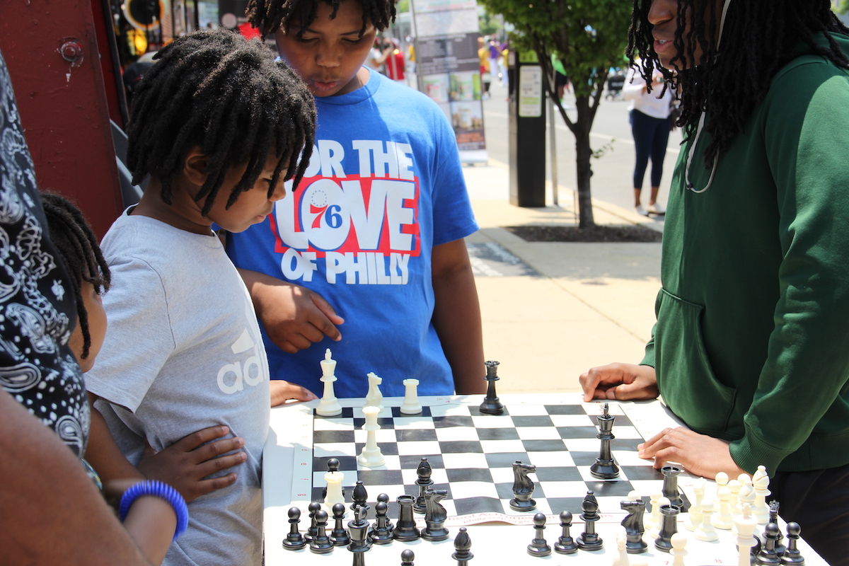 A child determines his next move in a game of chess on 52nd Street as the parade was going on