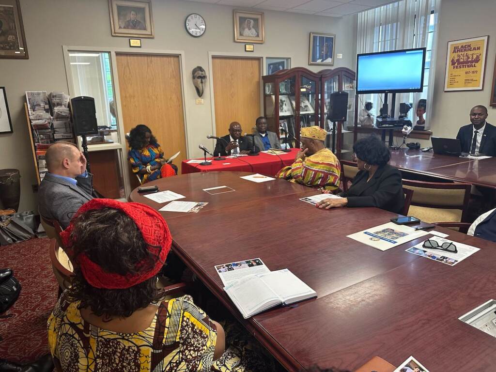 Mali Noel Diarra speaks in front of several people gathered around a roundtable.