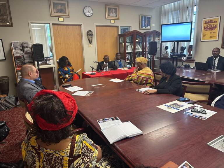 Noel Diarra speaks in front of several people gathered around a roundtable.