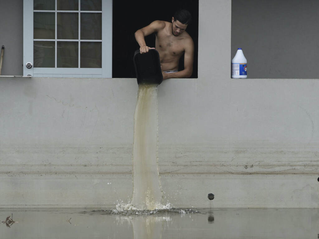 The Week That Was in Latin America Photo Gallery Man dumping water out of home in Catano, Puerto Rico