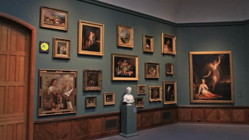This 19th century salon style installation in Gallery 6 is mimicked by KAWS across the room. (Kimberly Paynter/WHYY)