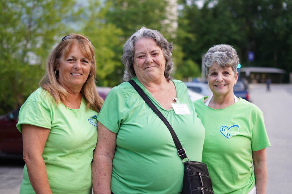 Three women in green shirts pose for a photo